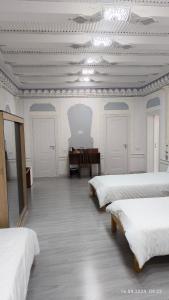 撒马尔罕比比克哈努姆酒店的一间设有四张床和一张桌子的房间