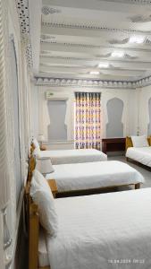 撒马尔罕比比克哈努姆酒店的一间设有四张床铺和白色床单的客房