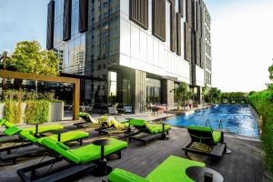 迪拜Revier Hotel - Dubai的一座带绿色躺椅的游泳池和一座建筑