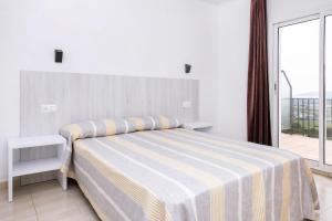 埃斯塔蒂特Apartamentos Torrevella的一间卧室配有一张带条纹毯子的床和窗户
