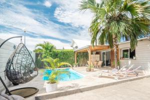 厄唐萨雷La Villa des Lataniers的一座带游泳池和棕榈树的房子