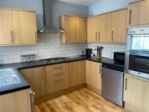 曼彻斯特Delightful home in Manchester的厨房配有木制橱柜和不锈钢用具