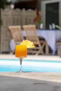 厄唐萨雷La Villa des Lataniers的坐在游泳池畔的桌子上喝一杯橙汁