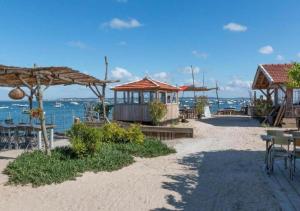 安德诺莱斯贝恩La Cabane de Didi的海滩上设有桌子和遮阳伞,还有大海