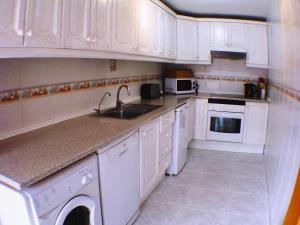 Las Lagunas MijasCasa Ladera的白色的厨房配有白色橱柜和水槽