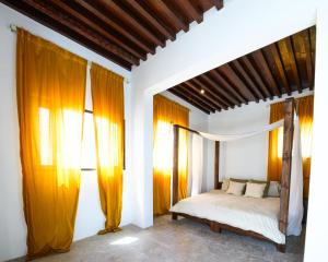 马斯喀特Salaam Space的一间卧室配有一张橙色窗帘的床
