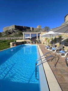 利尼亚雷斯Casa do Penedo Castle House的一个带椅子的游泳池以及一座房子