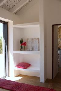 圣特奥托纽Beautiful country home immersed in nature的白色的房间,架子上有一个红色枕头