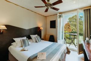 艾克斯莱班Hôtel L'Iroko The Originals City的一间卧室配有一张带吊扇和窗户的床。