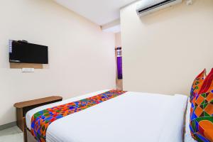 IrugūrFabExpress UV Residency的一间卧室配有一张带彩色毯子的床