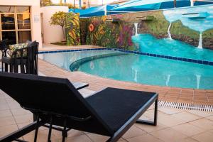 乌贝兰迪亚Hotel Golden Park Uberlandia的游泳池旁设有两把椅子和长凳