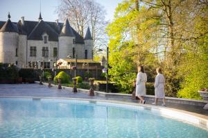 斯滕奥克尔泽尔毕佛特温泉酒店的两名妇女在城堡前的游泳池边散步