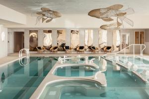 迪纳尔Emeria Dinard Thalasso Spa - Avril 2024 Réouverture après rénovation的游泳池,酒店内设有椅子和游泳池