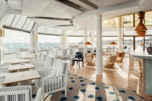 迪纳尔Emeria Dinard Thalasso Spa - Avril 2024 Réouverture après rénovation的餐厅设有白色的椅子和桌子以及窗户。
