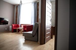 罗兹ADLER Bed&Breakfast的客厅配有椅子和红色椅子