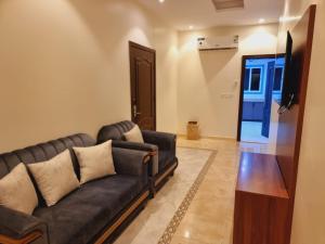 吉达الديار الفاخرة - الربوة的客厅配有黑色沙发和电视