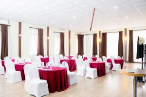 内罗毕韦斯特伍德酒店的一间设有红色和白色桌子及白色椅子的房间