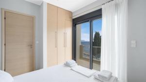 尼基亚娜Agni Suites的一间卧室设有大窗户和一张带两条毛巾的床