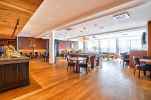 马恩河畔博纳伊克雷泰伊马恩河畔波涅基里亚德酒店的餐厅铺有木地板,配有桌椅