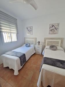 贝瑙汉Casa Rural La Escapadita的白色墙壁客房的两张床