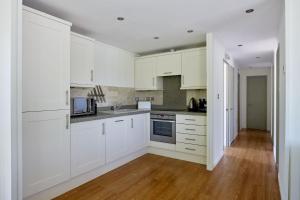 贝克因顿Farleigh Lodge的厨房铺有木地板,配有白色橱柜。