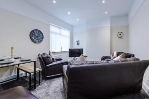 利物浦Cosy Modern 3-BR Apartment - Sleeps 5的客厅设有两张沙发和墙上的时钟