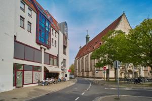 布伦瑞克City-Deluxe in Braunschweig的一条城市街道,有建筑,人坐在人行道上
