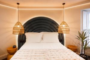 阿博伦Hive Townhouse的一间卧室配有一张大床和两个吊灯