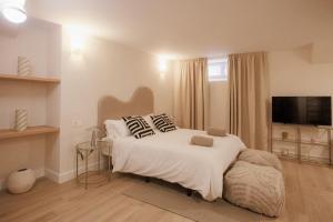 巴达霍斯Apartamentos Cervantes的卧室配有带枕头的白色床和电视。
