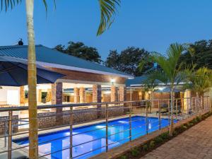 维多利亚瀑布The Shrub Lodge的一座酒店游泳池,在一座建筑前有棕榈树