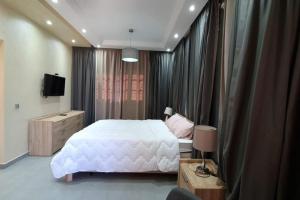 马拉喀什Belle Villa duplex avec piscine的卧室配有一张白色大床和电视。