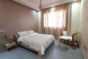 马拉喀什Belle Villa duplex avec piscine的卧室配有床、椅子和窗户。