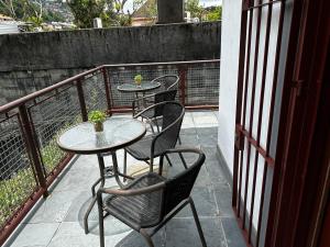彼得罗波利斯Village Hostel的阳台配有三张桌子和椅子