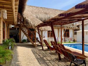 帕洛米诺Rincon del Mar Palomino的茅草屋顶和游泳池的度假村