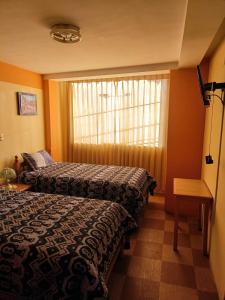 普诺Hostal Vista al Lago Titicaca Puno的酒店客房设有两张床和窗户。