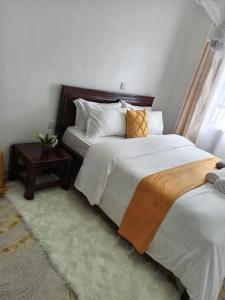 基塔莱Kai Suites Kitale的一间卧室配有两张床和一张边桌