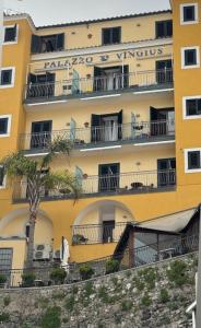 米诺利帕拉佐维吉优斯酒店的一座黄色的建筑,前面有棕榈树