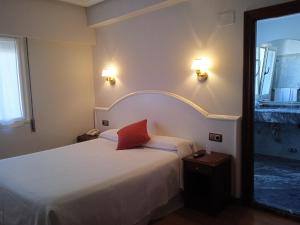 利亚内斯萨布隆酒店的一间卧室配有一张红色枕头的床