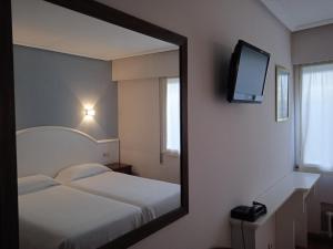 利亚内斯萨布隆酒店的镜子反射着一间卧室,配有一张床和电视