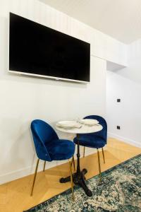 巴黎Chic Apartment in the Prestigious Saint Honoré的两把蓝色的椅子和一张桌子,墙上配有电视