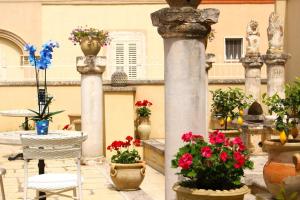 阿莱齐奥Palazzo Aurora的一个带鲜花和桌椅的庭院