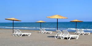 ErdemliDenizkumu Hotel的海滩上的一组椅子和遮阳伞