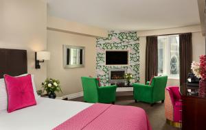 基拉尼罗斯酒店的一间卧室配有一张床、绿色椅子和壁炉
