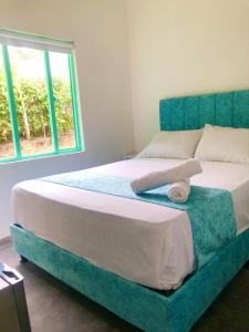 里考尔特Hotel Pallara Campestre的一间卧室配有一张带蓝色床头板的床和窗户