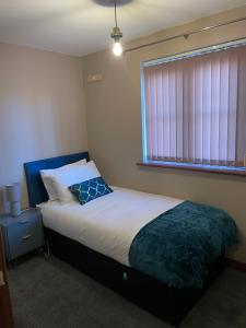 WhistonLanEnd House的一间卧室配有一张带蓝色床头板的床和窗户