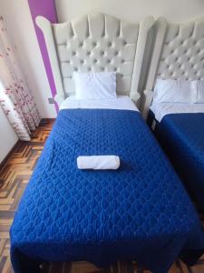 利马SUMAQ PUÑUY HOSTEL - LIMA AIRPORT的酒店客房,配有蓝色的床,上面有毛巾
