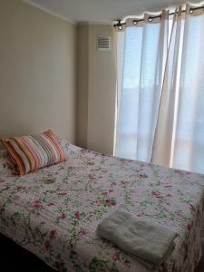 奥瓦列Ovalle Hotel Arauco的一间卧室配有一张带鲜花毯子的床和窗户。