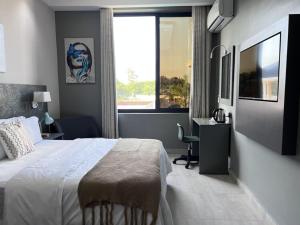 达累斯萨拉姆Serenity Suite With free Wi-Fi and Swimming pool的一间卧室配有一张床、一张书桌和一个窗户。