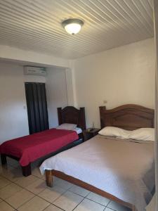 GuácimoHotel y restaurante Tabaconess的一间卧室配有两张床和红色毯子