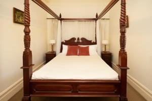 卢拉Leura House的一间卧室配有一张带红色枕头的四柱床